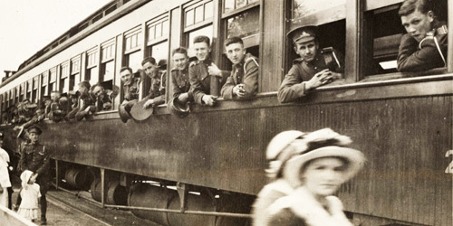 Canadian soldiers in Ontario lean out of a rail car as they depart for the coast circa 1915–1916. Soon, they will be boarding troop ships bound for England.