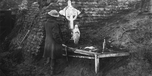 A Canadian takes a moment at the graveside of a Canadian who was killed in 2nd Battle of Ypres. November, 1917. Photo: Dept. of National Defence/LAC, MIKAN no. 3403359.